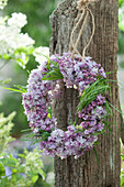 Wreath of lilac blossoms hanging from a tree stump