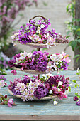 Spring table decoration on a cake stand with lilac blossoms, crabapple blossoms, and honesty flowers