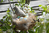 Osternest mit Vogelfigur und Schokoeiern im Birnbaum