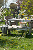 Easter table decoration in the garden: bouquet of flowering twigs and dandelions, Easter bunny, basket with Easter eggs and flower wreath