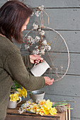 Frau gestaltet hängende Osterdeko auf der Terrasse