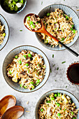 Mushroom fried rice presented in small bowls with soy sauce and scallion onions served alongside