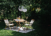 Tisch mit Stühlen auf Teppich im Garten