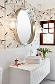 Washstand with round countertop sink below mirror and sconce lamps