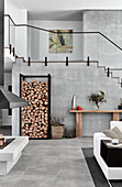 Stacked firewood against side wall in high-ceilinged interior