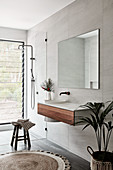 Floating washstand and mirror next to walk-in shower