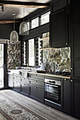 Fitted kitchen with dark cupboard fronts, tiles with tropical motif as splashback