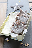 Gluten-free, homemade chocolate stars with powdered sugar in a metal tin