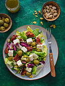 Salad with sundried tomatoes, olives, cheese and pistachios