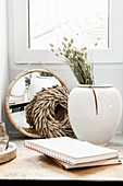 Vase mit Trockenblume, Kranz, Spiegel und Notizbücher