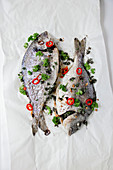 Fresh sea bream with parsley and chilis on paper