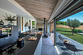 Elegante Küchenzeile in offenem Wohnraum vor Glasschiebetür und Terrasse