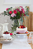 Beerentorte und sommerlicher Blumenstrauß auf Tisch