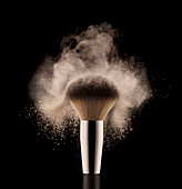 A close up of a powder brush on a black surface