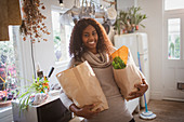 Happy woman with groceries in kitchen