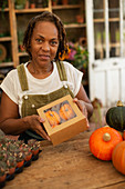 Female shop owner with box of pumpkins