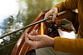 Man adjusting fly fishing line in boat