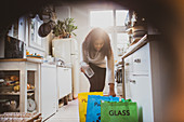Woman sorting recycling in bags on kitchen floor