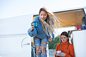 Young women friends drinking coffee in camper van