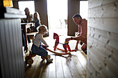 Family playing with rocking horse and toys in cabin