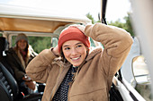 Happy young woman in stocking cap outside sunny van
