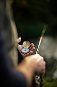 Man with fly fishing pole checking compass