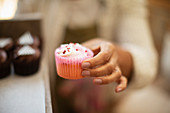 Female baker holding cupcake in pink liner