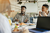 Business people talking at a breakfast meeting in an office