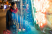 Young woman shopping at urban neon storefront at night