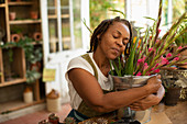 Woman hugging bucket of flowers in florist shop