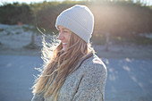 Happy young woman in knit hat on sunny beach