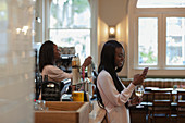 Young woman using smartphone and drinking wine in pub