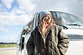 Confident young woman in coat outside sunny van
