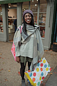 Happy young woman with shopping bag on sidewalk