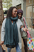 Happy mother and daughter with shopping bags on sidewalk