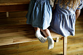 Girl in denim dress with dirty socks at wood dining table