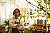 Confident female garden shop owner in greenhouse