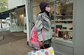 Young woman in face mask with shopping bags at storefront