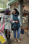 Mother and daughter with shopping bags walking arm in arm