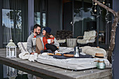Affectionate couple relaxing with coffee on patio cushions