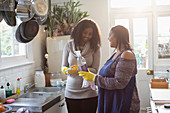 Mother and daughter cleaning with spray cleaner in kitchen