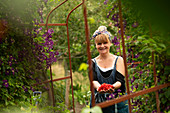 Proud woman harvesting fresh red currants in garden
