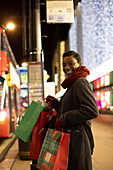 Happy young woman Christmas shopping on city sidewalk