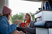 Young women friends eating instant noodles in camper van