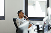 Businesswoman talking on telephone at computer desk