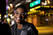 Happy young woman in funky eyeglasses in city at night