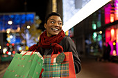 Happy young woman Christmas shopping in city at night