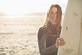 Happy young female surfer with surfboard on sunny beach