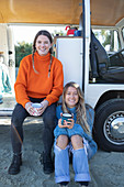 Happy young women friends drinking coffee at camper van
