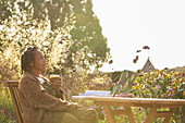 Woman with coffee working at table in sunny garden